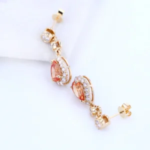 "Elevate your style with the AMIIZE Gold Filled Earrings, featuring a stunning pear-cut orange sapphire set in a 14k gold filled halo setting.