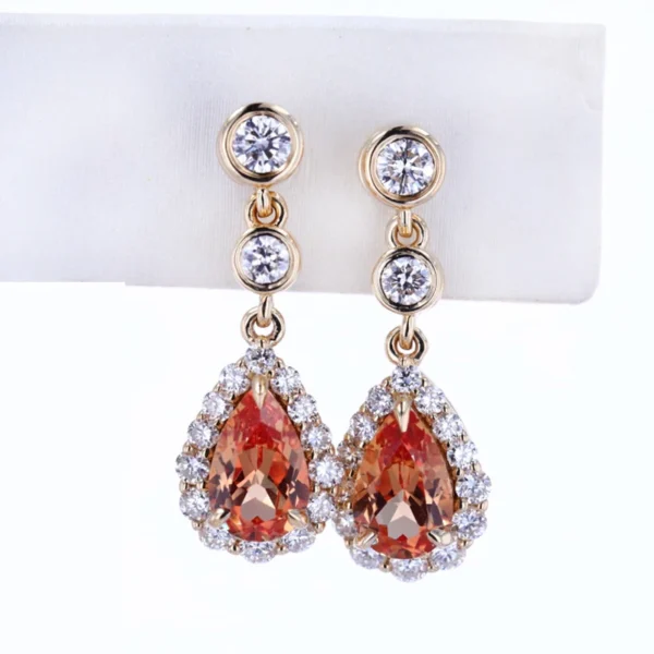 "Elevate your style with the AMIIZE Gold Filled Earrings, featuring a stunning pear-cut orange sapphire set in a 14k gold filled halo setting. - Image 4