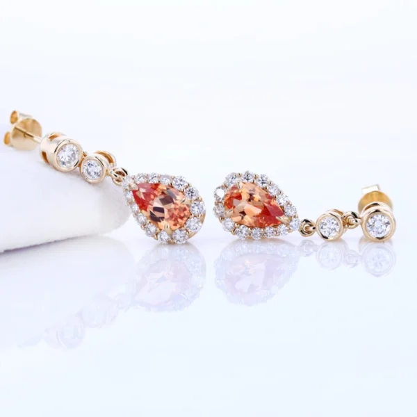 "Elevate your style with the AMIIZE Gold Filled Earrings, featuring a stunning pear-cut orange sapphire set in a 14k gold filled halo setting. - Image 3